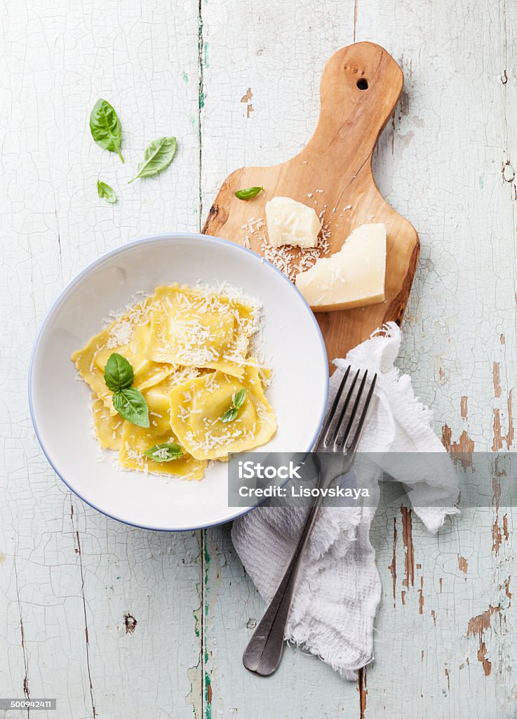 Ravioli pasta with parmesan cheese Ravioli pasta with cream sauce, basil and parmesan cheese on olive wood cutting board Ravioli Stock Photo