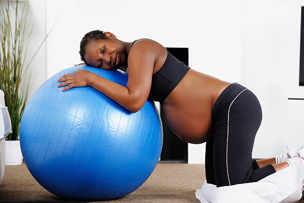African American Woman Using Swiss Ball During Labour A portrait of an African American woman using a Swiss ball during labour. home birth photos stock pictures, royalty-free photos & images