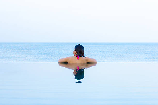 istock Woman looking out from infinity swimming pool 500944789