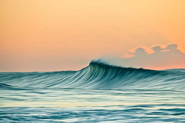 Photo of Wind swept breaking wave in the golden light of sunrise.