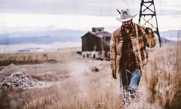 istock Man carrying pickaxe over shoulder walking through western field 500946049