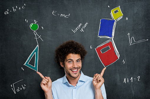 Portrait Of Happy Man Student With Books And Algebra Items Over A Blackboard