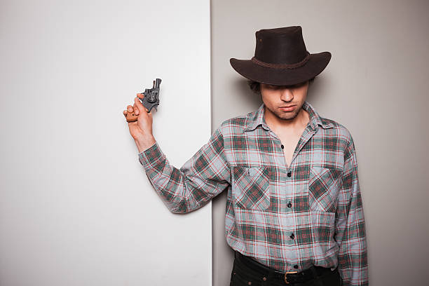 istock Young cowboy standing against dual colored background 500948381