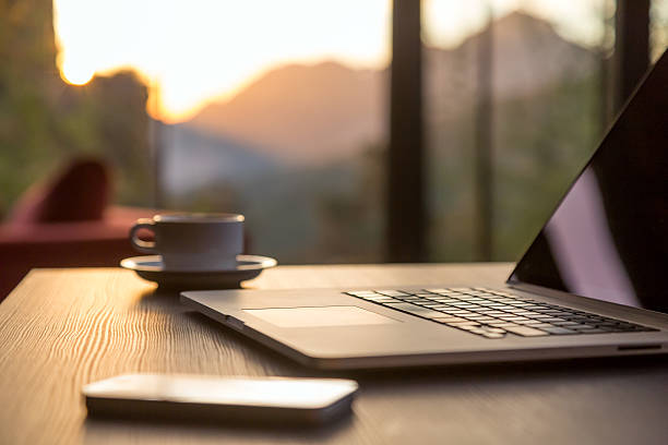 istock Computer Coffee Mug and Telephone black wood table sun rising 500954302