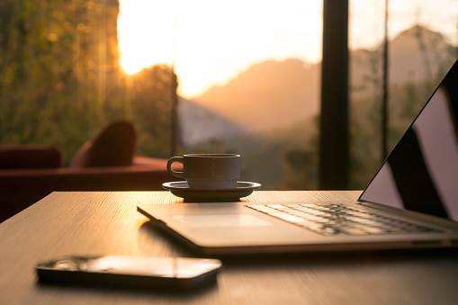 Ordenador con una taza de café en la mesa de madera y negra teléfono de sol creciente photo