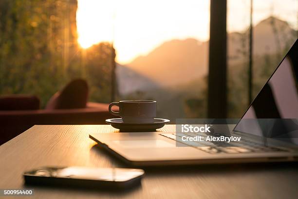 Computer Coffee Mug Telephone On Black Wood Table Sun Rising Stock Photo - Download Image Now