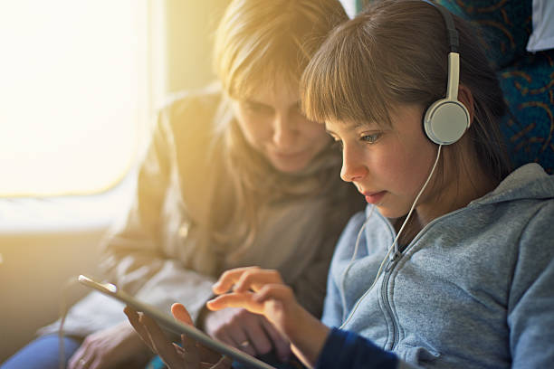 ragazza con madre in viaggio in treno e suona su tablet - video game family child playful foto e immagini stock