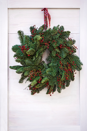 Green Christmas wreath hanging on white wooden door