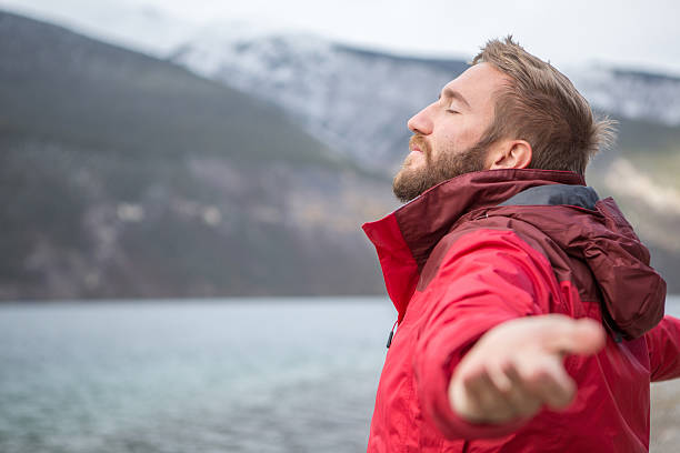 giovane uomo con le braccia tese lago per il relax - aspirations men human arm arms outstretched foto e immagini stock