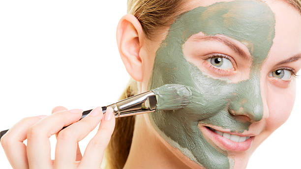 istock Woman applying with brush clay mud mask her face 500963794