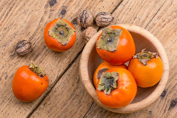 istock Fresh ripe persimmon on a wooden table - selective focus 500963994