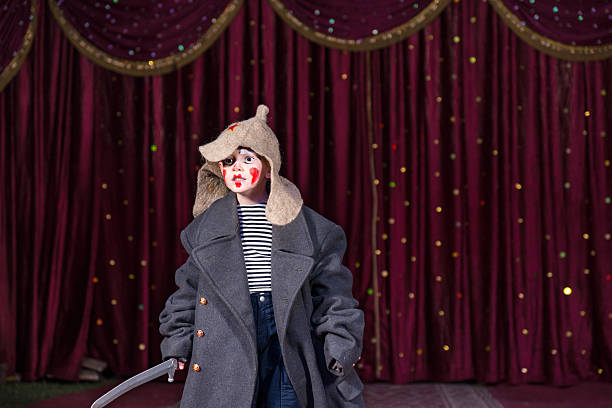 Skilled empathetic boy pretending to be a brave Russian soldier while performing a dramatic act, on stage, against dark red classical curtains