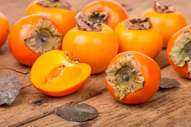 Fresh ripe persimmon on a rough, wooden, rustic table