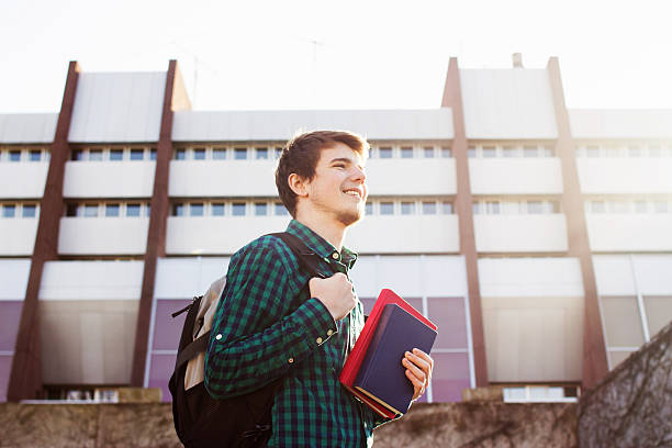 istock University.Smiling young  man holding a book 500965770