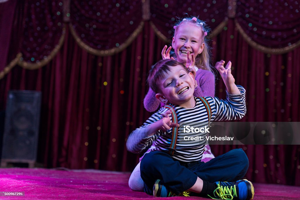 Two funny children acting as monsters on stage Two funny playful children, boy and girl, smiling while acting as monsters with claws, on a purple stage, in a theatrical representation Child Stock Photo