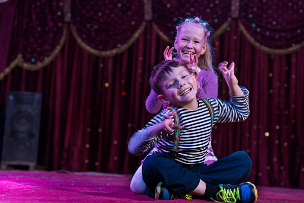 Two funny children acting as monsters on stage Two funny playful children, boy and girl, smiling while acting as monsters with claws, on a purple stage, in a theatrical representation theatrical performance stock pictures, royalty-free photos & images