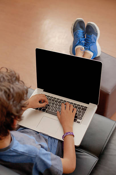 istock Latino boy sitting on sofa with laptop computer 500969004