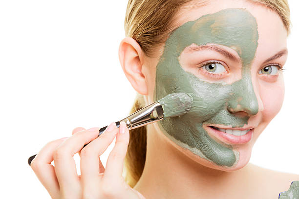 istock Woman applying with brush clay mud mask her face 500969860