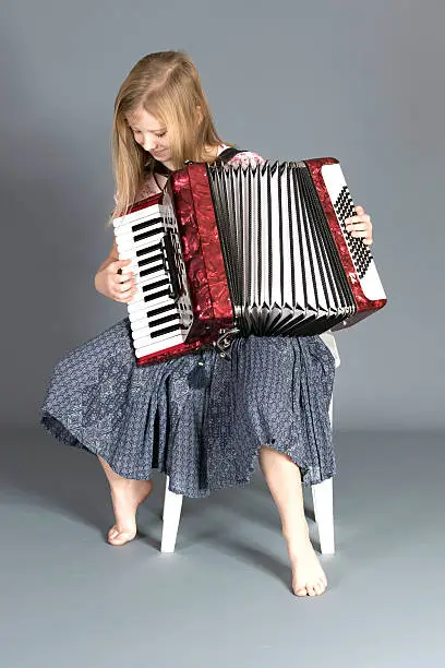 A girl focus on playing the accordion and making sure her fingers are positioned correctly.