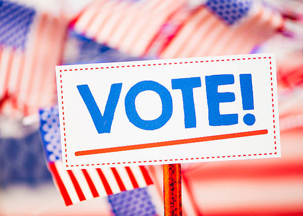 istock Vote sign with defcoused American flags in the background 500994768