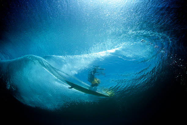 Underwater view of longboard surfer on a wave A backlit surfer glides over the wave on a single fin longboard longboarding stock pictures, royalty-free photos & images