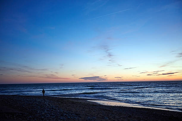 istock Fisherman walking on seashore at sunset 501003346