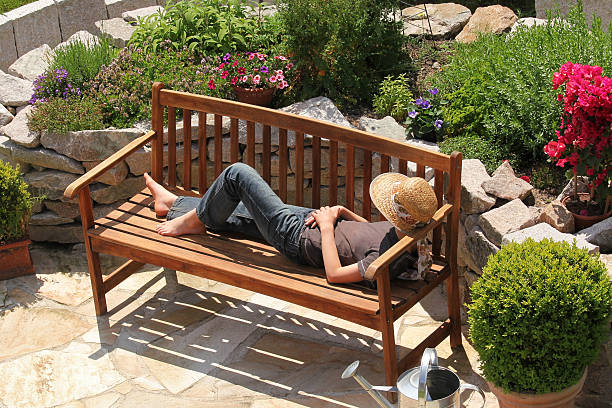 Relaxing on a garden bench Teenager with sun hut is chilling on a bench. ornamental garden stock pictures, royalty-free photos & images