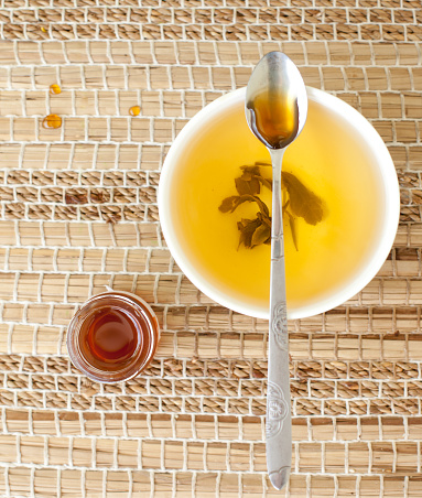 Green tea in a ceramic bowl with honey on a wooden background. Selective focus
