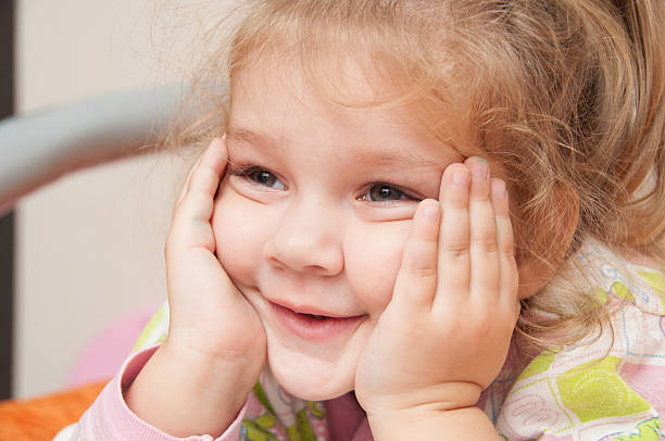 istock three-year girl interested looking at left hand propping cheek 501032930