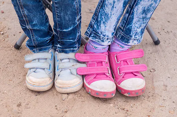 close-up of two pairs of children's feet girls dressed in jeans and sneakers