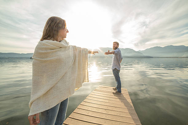 istock Couple on jetty, pulls out hands to reach each other 501036420