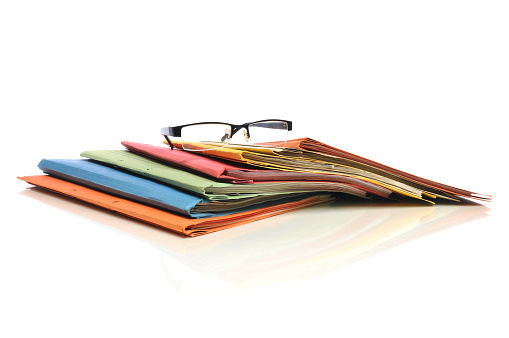 Multicolored office folders with glasses on white background