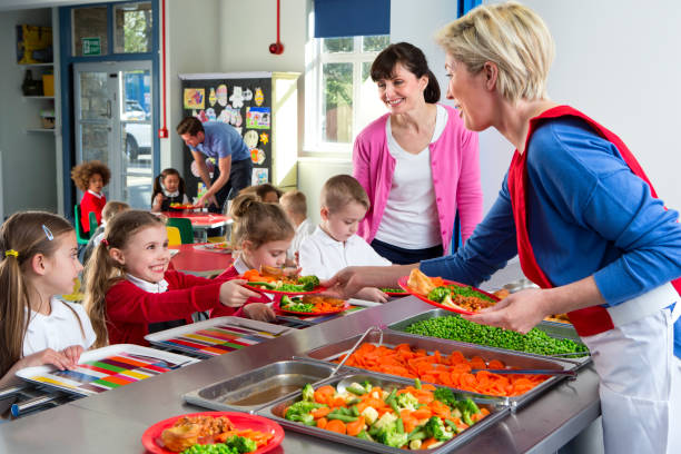 School Caferteria Line Dinner is served out to children as they line up at a school canteen cafeteria worker photos stock pictures, royalty-free photos & images