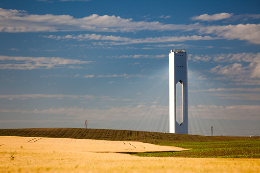 Solar Tower with rays  - thermo-solar power - blue sky and yellow field - horizontal