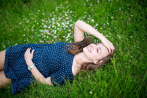istock Smiling young girl lying on green grass 501058223