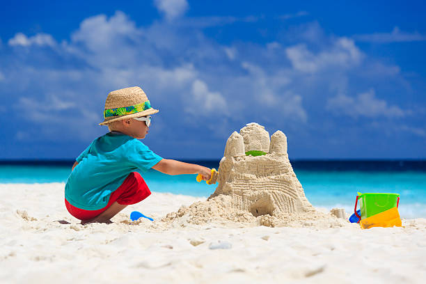 ребенок здание песка замок на тропический пляж - lifestyles child beach digging стоковые фото и изображения