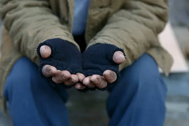 Man in need. Unhappy homeless man is holding hands to get help.