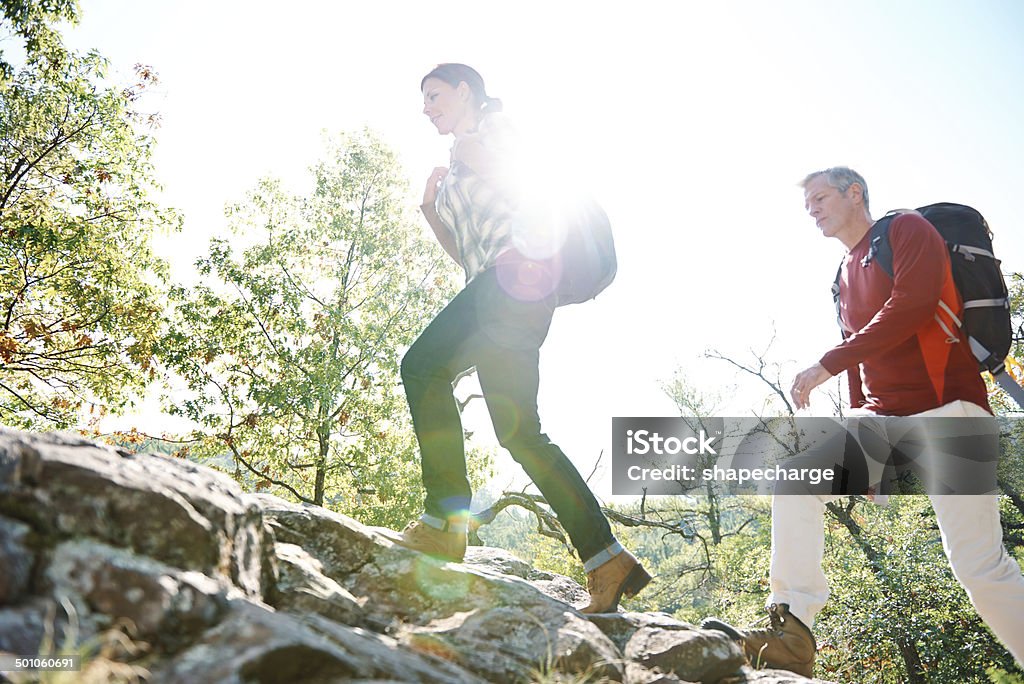 Take that mountain one step at a time Low angle shot of a couple hiking uphill on a sunny day Active Lifestyle Stock Photo