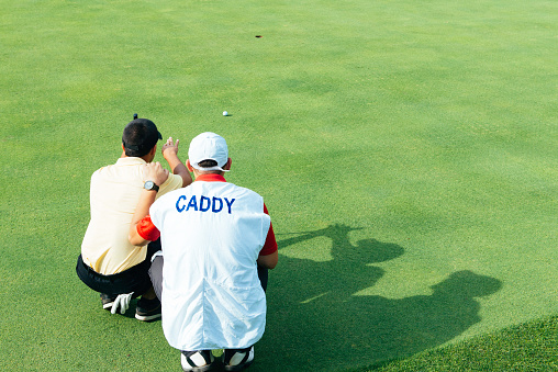 Golfer and caddy reading green