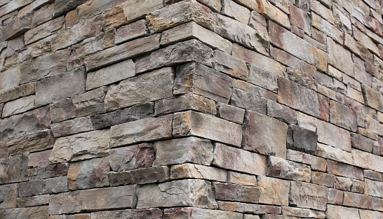 Rock wall created with rectangular rock bricks - perspective view on a corner