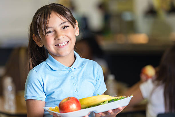 linda escola primária de estudante segurando a bandeja de comida em sala de almoço - tray lunch education food - fotografias e filmes do acervo