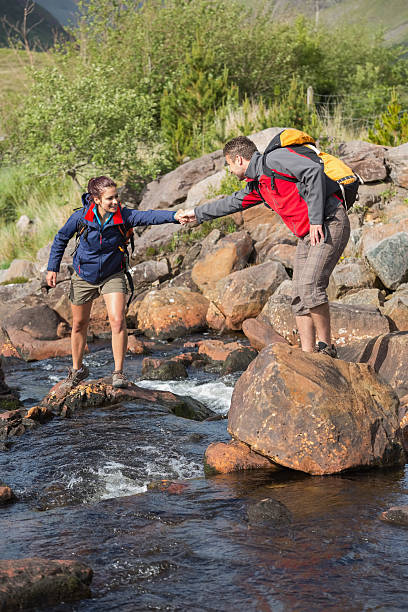 istock Man helping his girlfriend to cross a river 501063143
