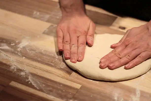 Photo of Woman hands kneading pizza dough on wooden kitchen table