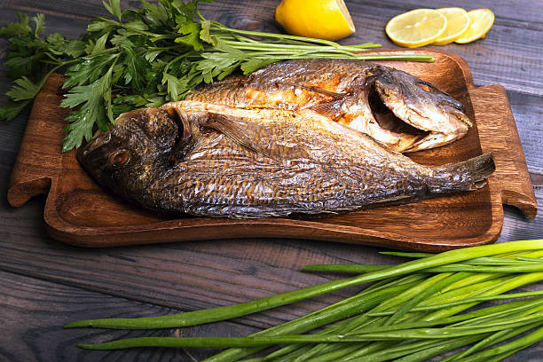 istock wooden table plate with two roasted carp fish dorado 501068036