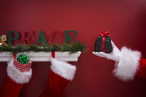 istock Santa's hand holding coal next to Christmas Stockings 501069556