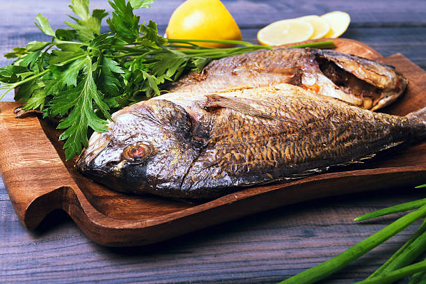 istock wooden table plate with two roasted carp fish dorado 501070084