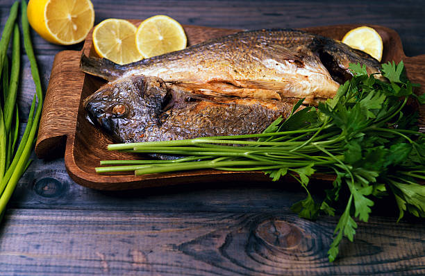 istock wooden table plate with two roasted carp fish dorado 501070414