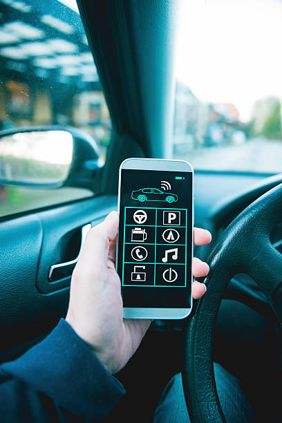istock Man sits inside car and controls it with smart phone 501070666