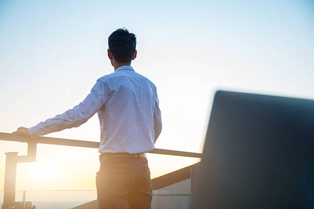 Thoughtful Young Professional Overlooking Downtown at Sunset stock photo