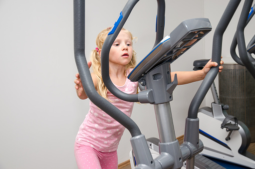 little blond girl training in equipment in the gym